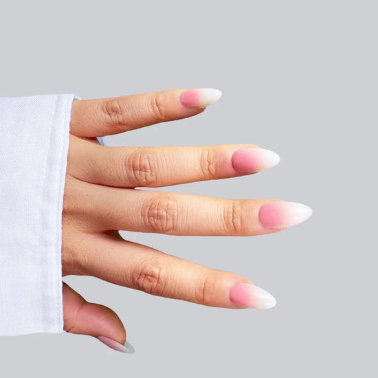 Open horizontal hand showing Blush Elise soft baby pink to sheer white ombre short almond press-on nails with white sleeve
