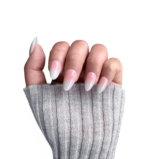 Blush Elise short almond press-on nails showing baby pink to white ombre gradient, closed fist pose with grey knit sleeve