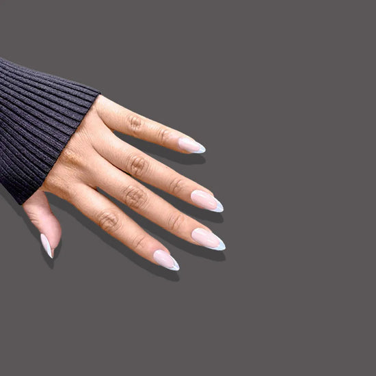 Side spread hand showing de blinkie Blush Mirage warm nude and aurora iridescent French tip press-on nails in short almond against a dark charcoal grey background with a black ribbed knit sleeve