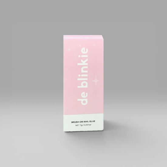 Front of de blinkie Brush-On Nail Glue 7g box in pink and white against a grey background