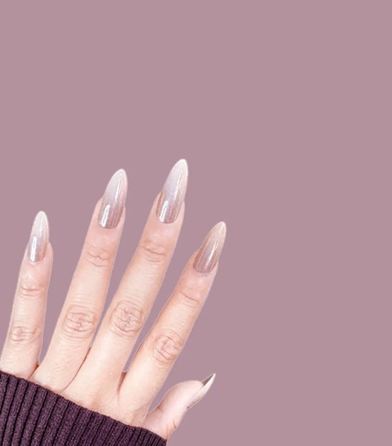 Diagonal hand pose showing de blinkie Champagne Veil champagne gold glazed ombre press-on nails in medium almond shape against mauve background with dark ribbed knit sleeve