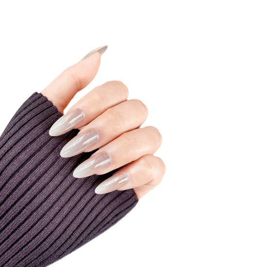 Fingers up pose showing de blinkie Champagne Veil champagne gold glazed ombre press-on nails in medium almond shape against white background with dark ribbed knit sleeve