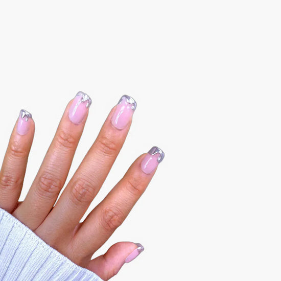 Fingers up pose showing de blinkie Chrome Whispers sheer blush pink with sculptural silver chrome tips in short square shape against white background with white ribbed knit sleeve