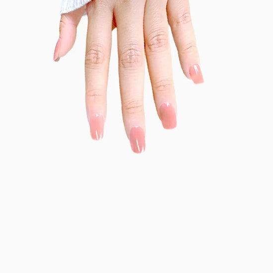 Downward spread hand showing de blinkie Cinnamon Glaze warm cinnamon rose press-on nails in short square against a clean white background with a white ribbed knit sleeve