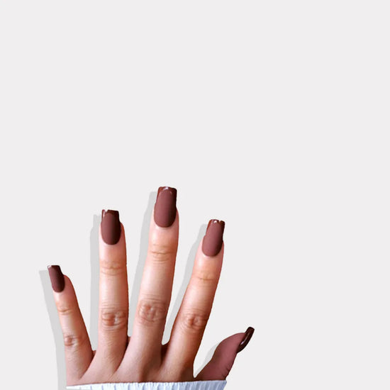 Fingers up pose showing de blinkie Cocoa Suede rich chestnut velvet matte press-on nails in medium square shape against grey background with white ribbed knit sleeve
