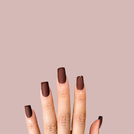 Fingers up pose showing de blinkie Cocoa Suede rich chestnut velvet matte press-on nails in medium square shape against pink background with white ribbed knit sleeve
