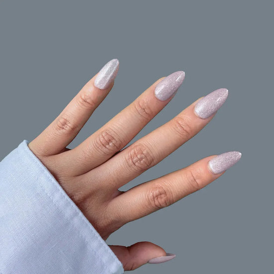 Upward diagonal pose showing de blinkie Crystal Muse icy silver crushed crystal shimmer short almond press-on nails against grey background