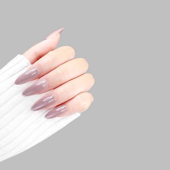 Claw pose showing de blinkie Dame Allure velvet mauve rose press-on nails in short almond against a soft grey background with a white ribbed knit sleeve