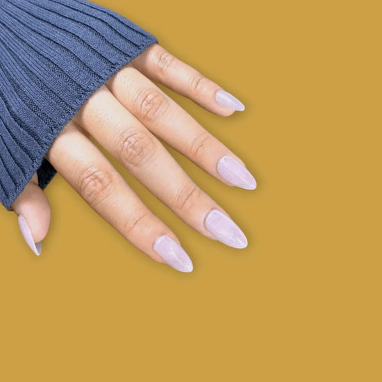 Downward hand pose showing Glazed Rosé soft rose pink glazed shimmer short almond press-on nails against mustard yellow background with navy sleeve