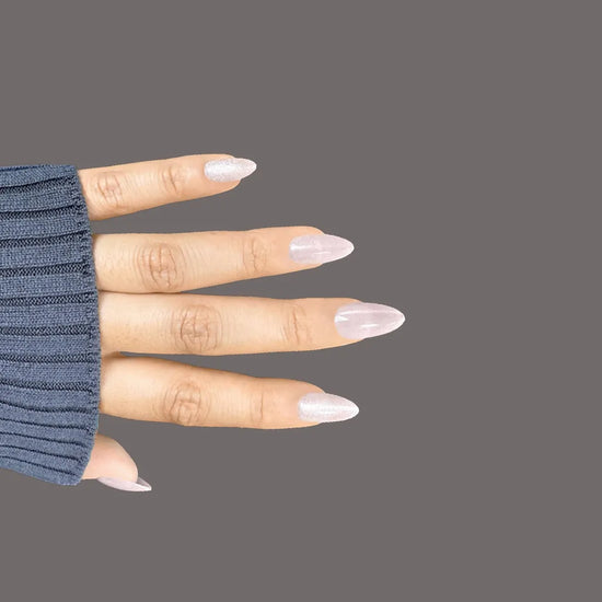 Horizontal spread hand showing Glazed Rosé sheer rose pink pearlescent shimmer short almond press-on nails against grey background with navy sleeve