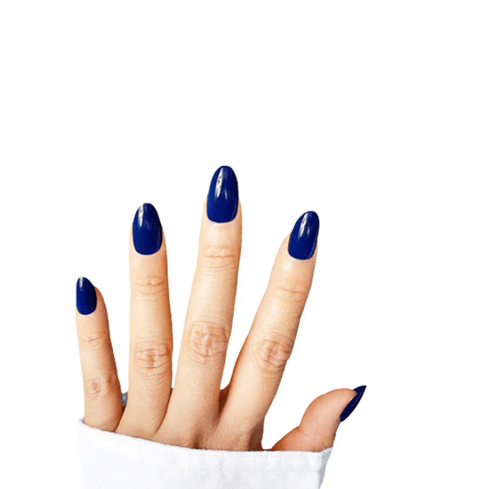 Fingers-up pose showing de blinkie Indigo Ivy rich indigo blue press-on nails in short oval shape against white background with white denim sleeve