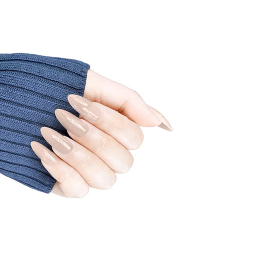 Claw pose showing de blinkie Lady Aurora sheer nude press-on nails in medium almond against a white background with a navy ribbed knit sleeve