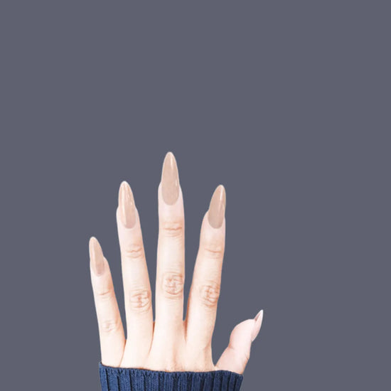 Spread hand showing de blinkie Lady Aurora sheer nude press-on nails in medium almond against a soft grey background with a navy ribbed knit sleeve