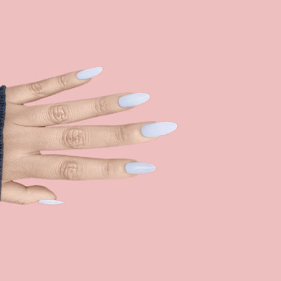 Spread hand showing de blinkie Lady Ivory creamy milky white press-on nails in medium oval shape against soft pink background with dark charcoal ribbed sleeve