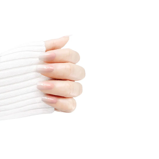Claw pose showing de blinkie Mademoiselle Glow soft peach nude to white ombre press-on nails in short square against a white background with a white ribbed knit sleeve