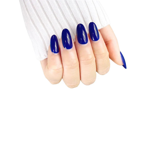 Claw pose left-facing showing de blinkie Midnight Reign cobalt blue gloss press-on nails in short oval against a white background with a white ribbed knit sleeve