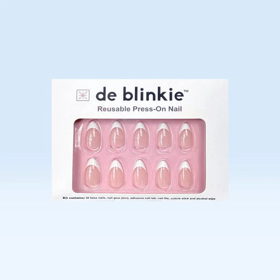 Product box shot of de blinkie Miss Classé sheer blush white French tip reusable press-on nails in short almond displayed in white branded packaging on a pink tray against a soft blue background