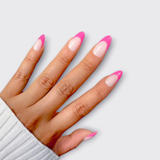 Horizontal spread hand showing de blinkie Miss Fuchsia Flick sheer nude base with electric pink curved French tip press-on nails in short almond shape against light grey background with white linen sleeve