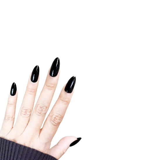 Fingers pointing upward showing de blinkie Miss Noir onyx gloss black press-on nails in short almond against a white background with a charcoal ribbed knit sleeve