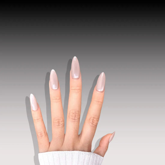 Horizontal spread hand showing de blinkie Miss Opaline velvet champagne nude press-on nails in short almond against a black to grey gradient background with a white ribbed knit sleeve
