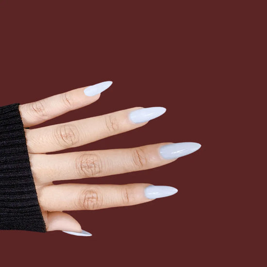 Horizontal spread hand showing Miss Serene soft milky white medium almond false nails against deep red background with black sleeve