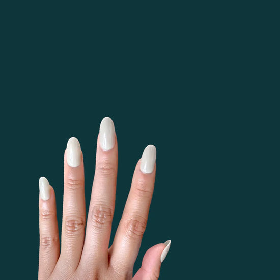 Diagonal spread hand showing de blinkie Olive Dusk muted olive grey press-on nails in short oval against a deep teal background