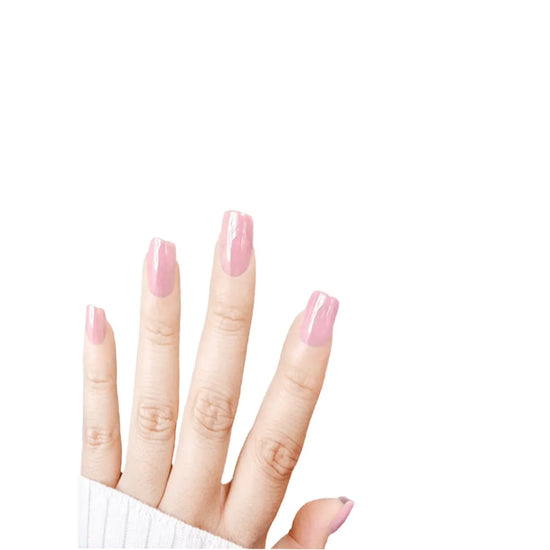Fingers spread upward showing de blinkie Pink Glimmer soft bubblegum pink glazed press-on nails in short square against a white background with a white ribbed knit sleeve