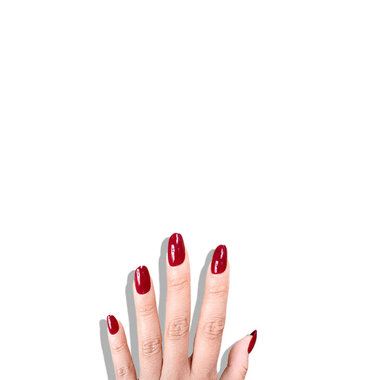 Fingers up pose showing de blinkie Scarlet Muse classic crimson gloss press-on nails in short oval against a light grey background with a white ribbed knit sleeve