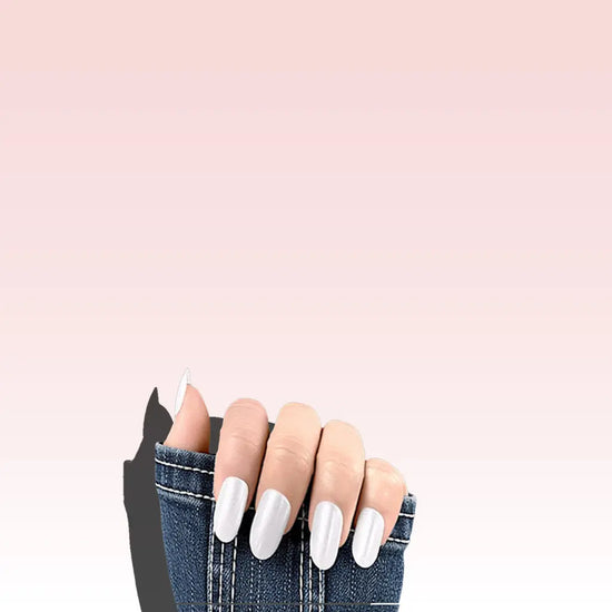 Claw pose showing de blinkie Silver Glint pearl white pearlescent press-on nails in short almond with a denim jacket sleeve