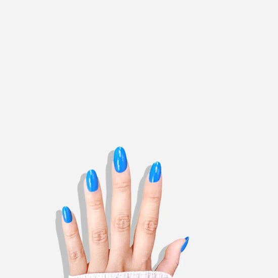 Fingers down pose showing de blinkie Skyline Pop vivid azure blue gloss press-on nails in short oval against a white background with a white ribbed knit sleeve