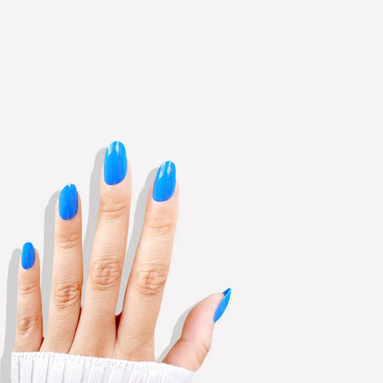 Fingers up pose showing de blinkie Skyline Pop vivid azure blue gloss press-on nails in short oval against a white background with a white ribbed knit sleeve
