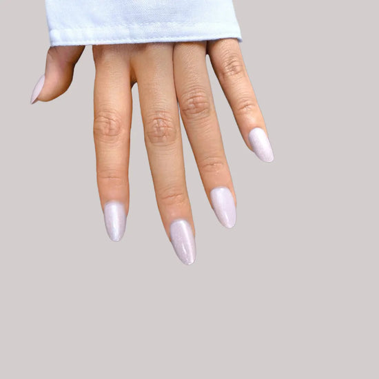 Fingers pointing down showing de blinkie Sugar Glaze frosted pale lilac blush silver shimmer short oval press-on nails against grey background with light blue sleeve