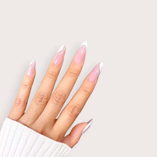 Upward spread hand showing de blinkie Swirl Baddie sheer pink base with white French tip and swirl nail art press-on nails in medium almond against a soft light grey background with a white ribbed knit sleeve