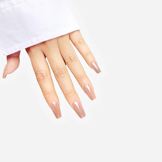 Fingers-spread down pose showing de blinkie The Executive Nude warm beige nude press-on nails in short coffin shape against light grey background with white sleeve