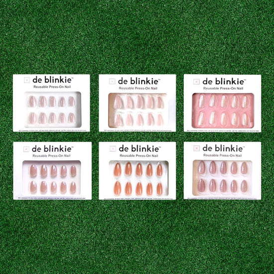 Box shot showing all six de blinkie The Glazed Hit glazed press-on nail styles against a grass green background