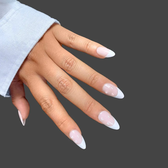 Elegant short almond press on nails with milky white French tips soft blush nude base and pearl accents